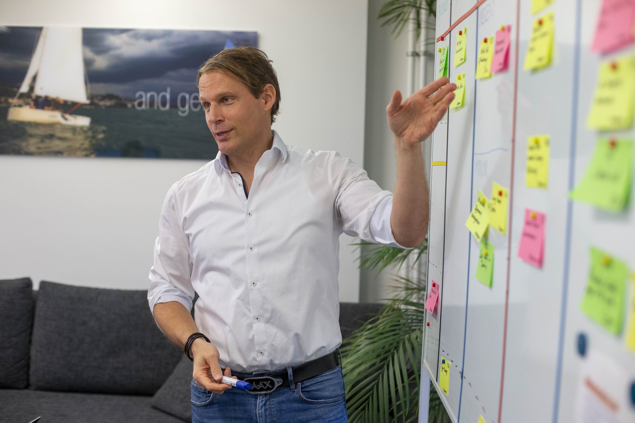 Mann steht vor einem Board, welches imt Post-Its beklebt ist.