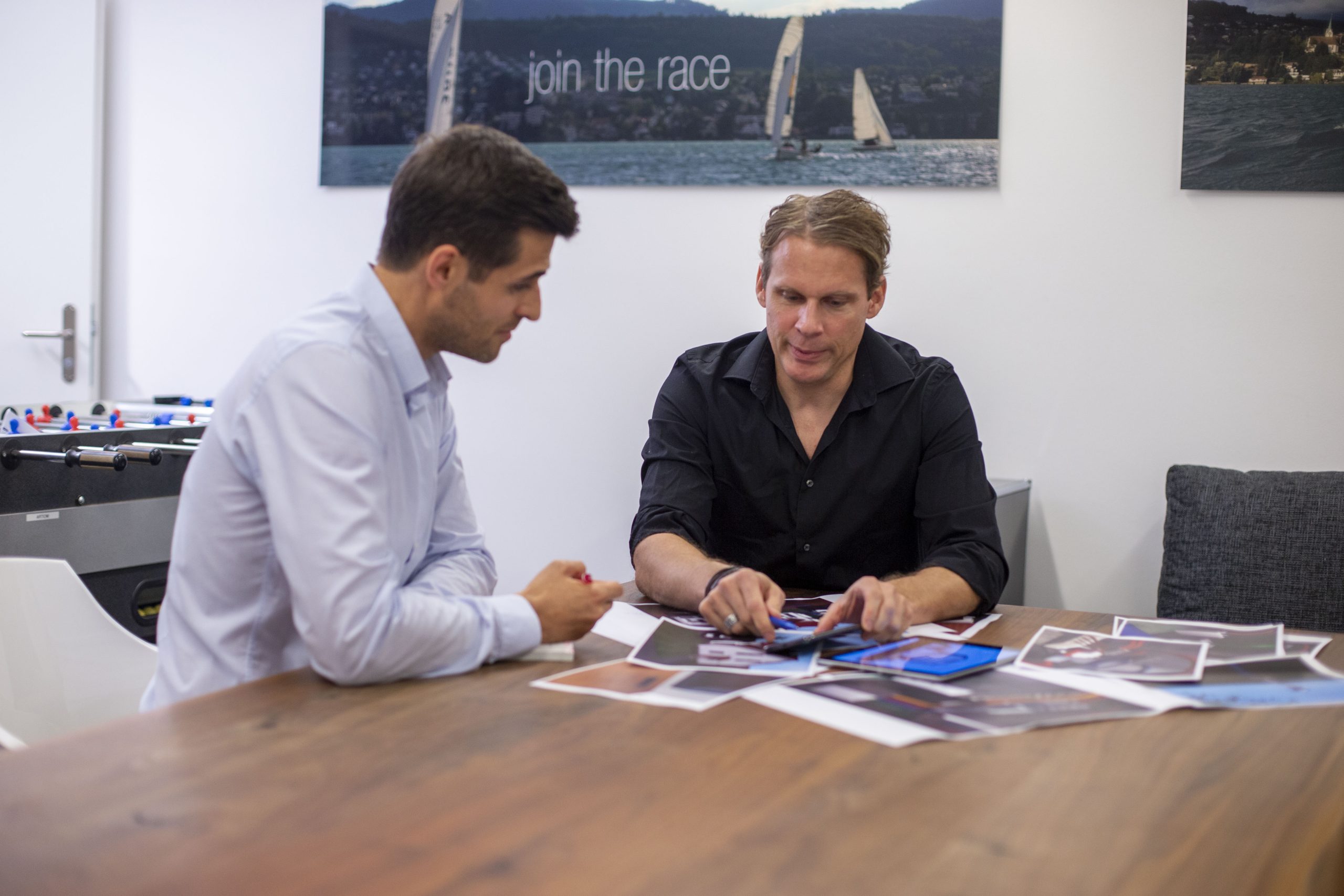 zwei Menschen, die ein Beratungsgespräch führen.Vor ihnen liegen Dokumente auf einem Holztisch